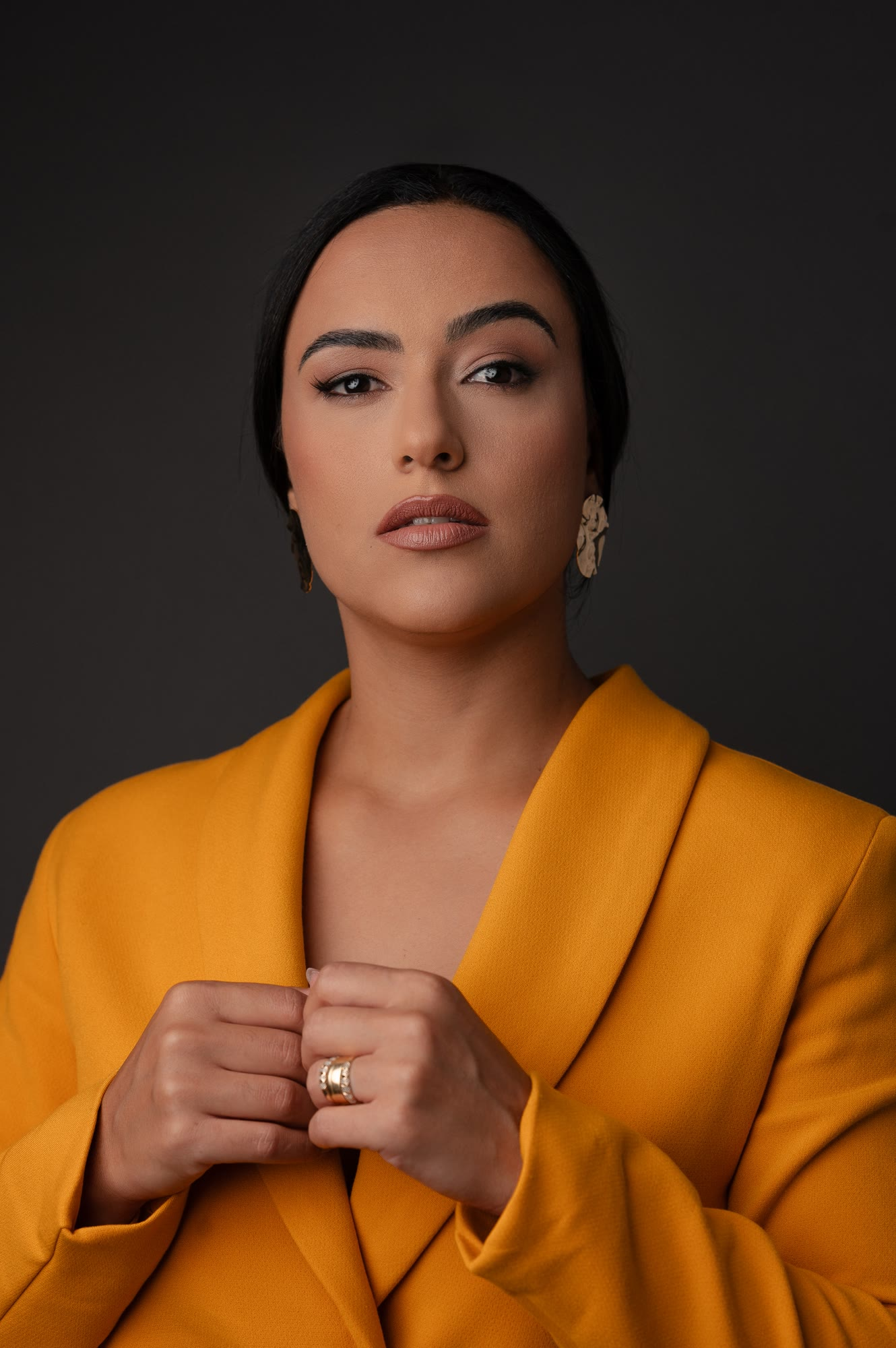 Camila Meneses de blazer mostarda, em retrato de estúdio